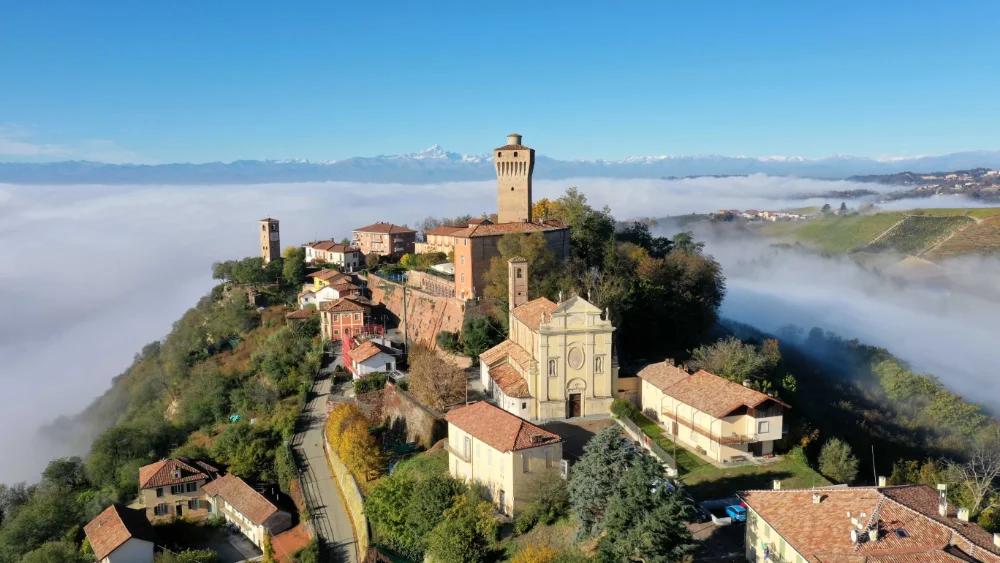 Un borgo in collina che emerge dalla nebbia